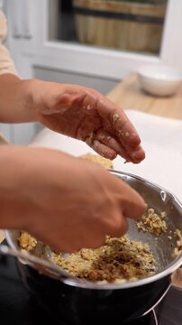 A woman is making a dish in a pan. The pan is filled with a mixture of ingredients, including nuts and fruit. The woman is holding the pan in her hands, and the dish appears to be a healthy