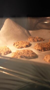 A tray of cookies is baking in an oven. The cookies are golden brown and appear to be ready to be taken out