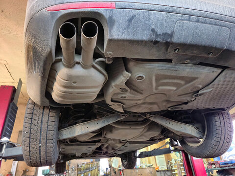 Underside view of a car on a lift, showing exhaust system and suspension components