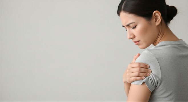 Young asian woman suffering from shoulder pain, touching her hurting arm. Health care and medical concept for symptom examination.
