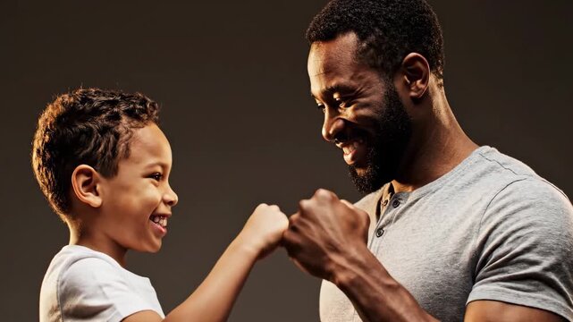 Joyful African American Father and Son Fist Bumping in a Studio Setting.