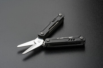 Compact black multi-tool isolated on black background. Features pliers, knife, file, and screwdrivers. Versatile portable gear for repair and hiking. EDC. Everyday Carry.