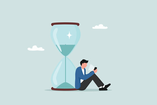 The concept of screen time, doom scrolling or wasting time using smartphone, phone addiction, exhausted man sitting with hourglass while using smartphone with bright light on his face.
