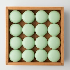 A wooden box filled with round green macarons arranged in a grid pattern.