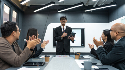 Happy diverse Asian business team analyzing financial statistics in office.