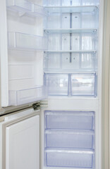 Fototapeta premium Modern open refrigerator close-up with empty shelves, front view.