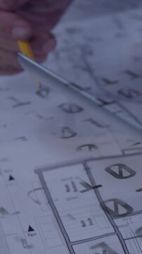 Vertical video: Architect hand entering marking plans with yellow pencil using compass for revision