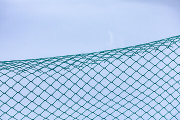A green mesh fence with a blue sky in the background