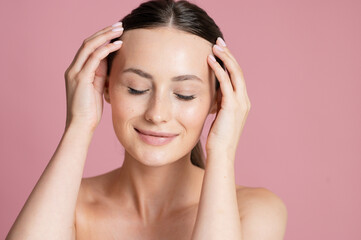 Naklejka premium Young woman with closed eyes and hands on temples, enjoying a moment of peace and self-care