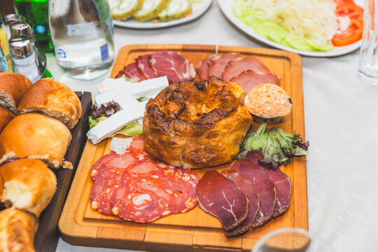 Traditional Balkan appetizer platter with cured meats, white cheese, and baked pastry.