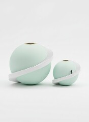 Two spherical objects with white accents on a plain surface viewed from a slightly elevated angle