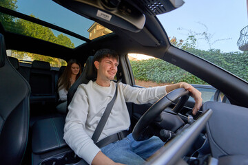 Young couple enjoying road trip driving car with sunroof