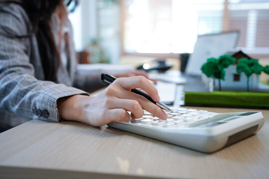 Business mortgage realtor with house model, sitting at desk, real estate agent manager working on calculator and documents, mortgage and property