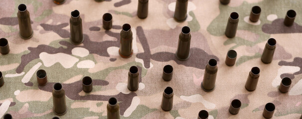 Big amount of shells cartridges from assault rifle bullets on old camouflage fabric