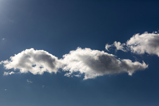 Trois nuages blancs lumineux en bande au centre de l'image dans un grand ciel bleu