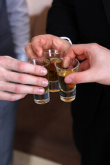 Men raise glasses with drink for a festive toast before the wedding event.