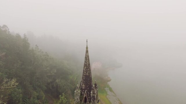 Close aerial view of chapel tower near Furnas Lake in misty landscape Sao Miguel Azores