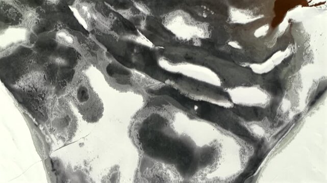 A top down, aerial view of a frozen lake on Long Island on a cloudy morning with snow. The drone camera, tilted straight down dolly in over the frozen lake.