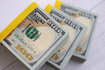 Three packs of ten thousand US dollar bills on wooden background. Packs of hundred dollar bills in stack on white wood planks close up © mehaniq41