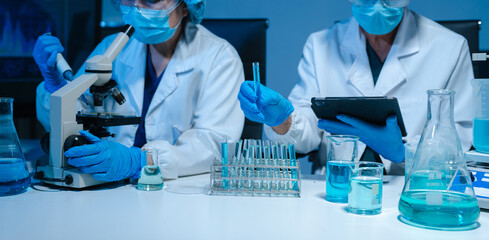 Scientists conducting research in a biotechnology lab, using pipettes and test tubes for medical...