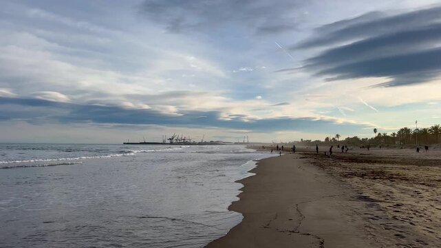 People on a sunny winter day actively relax with their families. A day off on the beach of the Mediterranean Sea in winter. Grao. Castellon de la Plana. Valencia. Spain