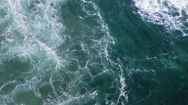 Top down drone view of swirling Atlantic water and turbulent wave patterns near Nazar&eacute;