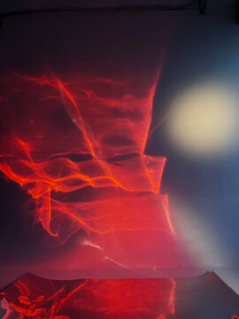 Vibrant abstract light patterns on a reflective liquid mirror surface in a studio, created with colored lighting