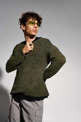 Obraz premium Stylish curly man showcases trendy outfit in a modern studio setting