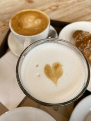 Coffee cups with latte art and pastry on dark wooden table