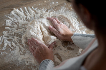 Fototapeta premium Woman kneading dough in kitchen preparing homemade bread