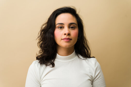 Portrait of a woman standing in a studio, modeling her natural look and confidence with a casual pose and serious gaze