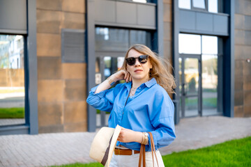 Fototapeta premium Woman holding hat and looking forward in modern residential district. Freedom from debt and successful mortgage completion concept.