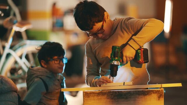 Young boy learning woodworking using power drill