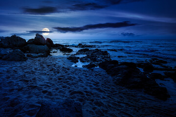 sandy beach landscape at night. full moon over coastal seascape scenery. mysterious nature...