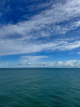 Ocean and blue sky with fluffy clouds.