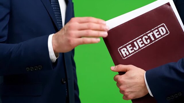 Businessmen's hands exchanging a "REJECTED" document, symbolizing corporate denial, refusal, or an unsuccessful proposal.