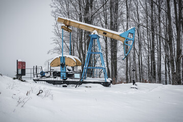 Abandoned blue yellow oil pump in winter mountains