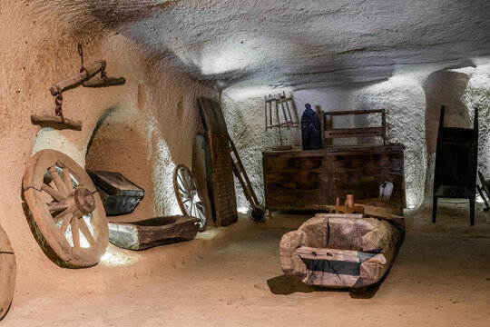 Museum inside the Uchisar castle. Antique kitchen utensils, furniture, wheels, scales, trough, wooden chest and grain slide. Interior of the rock-hewn house in Cappadocia, Turkey.