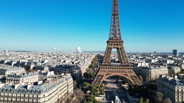 Iconic Eiffel Tower rising above Paris rooftops under blue sky