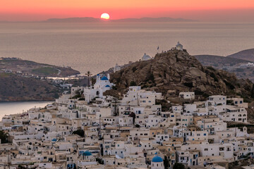 Panoramic view of the beautiful whitewashed village also known as chora, in Ios Greece, and a spectacular orange sunset in the background
