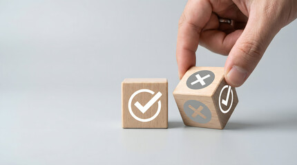 Hand chooses between checkmark and cross symbols on wooden blocks