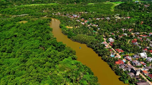 Aerial view of the Nilwala River winding through lush green vegetation and small houses near Matara, Sri Lanka.
