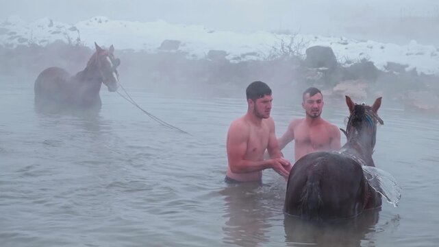 A man climbs onto a horse and prepares to jump into a steaming natural thermal spring in winter. Snowy landscape and rising mist create a dramatic and adventurous outdoor scene.