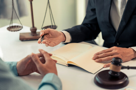 The lawyer is pointing out the signature points on a legal document with a pen during a legal consultation meeting, representing the client in court and assisting with legal documents.