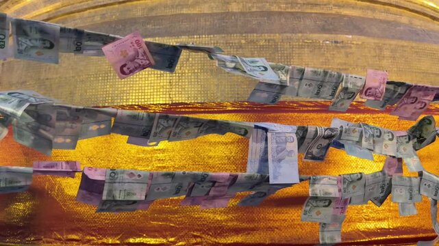 Thai banknotes attached as symbolic offerings at Golden Mount temple in Bangkok, Thailand. Traditional Buddhist donation ritual at Wat Saket during sunset.