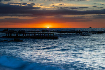 Fototapeta premium Amazing colourful sunrise seen over the Mediterranean Sea from Barceloneta Beach, which is located next to Barcelona's classic fishing quarter. It is the cities oldest and best-loved beach and gives w