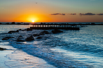 Naklejka premium Amazing colourful sunrise seen over the Mediterranean Sea from Barceloneta Beach, which is located next to Barcelona's classic fishing quarter. It is the cities oldest and best-loved beach and gives w