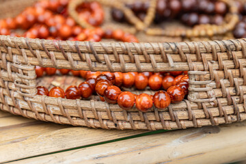 Wooden bead bracelets with warm amber tones inside a woven wicker basket at the Buddhist souvenir...