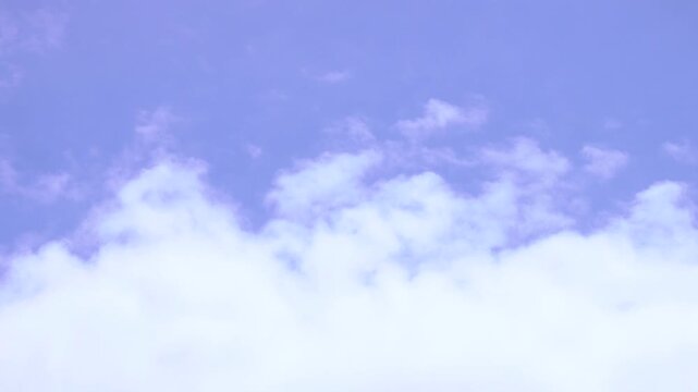 The clouds move from left to right, blown by the wind. The background is a blue sky in summer.