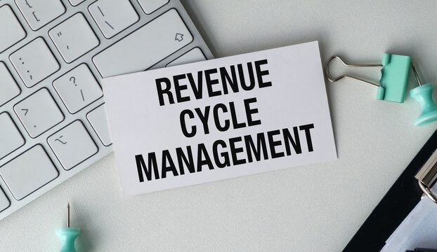 Revenue cycle management text on a card placed on a white desk next to a keyboard.